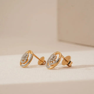 Side view of yellow gold swirl floral diamond earrings featuring a raised clustered centre and pavé-set diamond curves, highlighting depth and layered craftsmanship on a neutral surface.