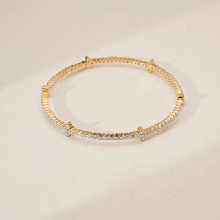 Top view of yellow gold diamond bangle featuring a continuous line of round lab grown diamonds with floral cluster accents, arranged in a sleek circular silhouette on a neutral surface.