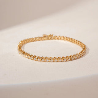 Top view of a 14KT Dual Gold diamond tennis bracelet featuring a continuous row of round diamonds in bezel settings.