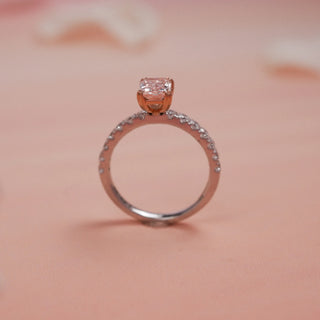 Side view of Reia Rose Glow Radiant Diamond Ring on a blush-peach background, showing the elevated pink centre stone set in a rose-tinted prong atop a diamond-studded 14KT white gold band.