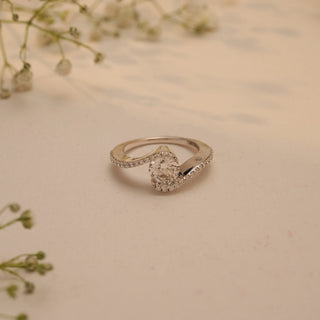 Top view of Reia's Twilight Embrace Diamond Vow Ring, crafted in 14KT white gold with a round-cut lab-grown diamond framed by curved pave bands, on a beige floral background.