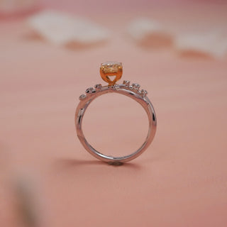Side view of Reia Sunlit Glow Radiant Diamond Ring on a blush-peach background, highlighting the raised yellow radiant-cut centre stone in a gold prong setting atop a 14KT white gold diamond band.