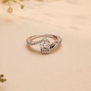 Top view of Reia's Twilight Embrace Diamond Vow Ring, crafted in 14KT white gold with a round-cut lab-grown diamond framed by curved pave bands, on a beige floral background.