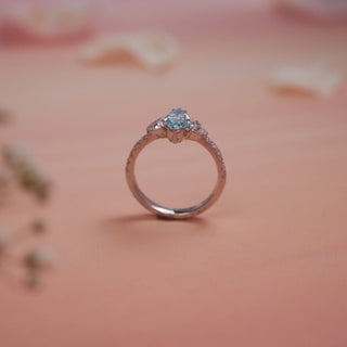 Angled view of Reia Aqua Trine Marquise Diamond Ring on a blush-peach background, showcasing the balance of marquise and trilliant diamonds with pave-set accents on a graceful 14KT white gold band