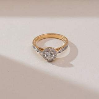 Top view of Sophisticated Circular Halo Diamond Ring in yellow gold, featuring a round lab-grown diamond surrounded by a sparkling halo with diamond-set shoulders, placed on a soft beige backdrop.