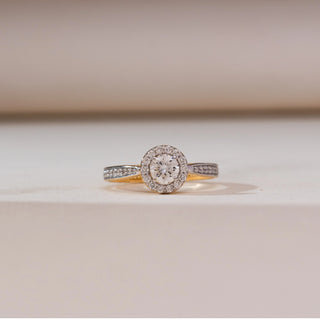 Front view of Sophisticated Circular Halo Diamond Ring in yellow gold, highlighting a round lab-grown diamond framed by a sparkling halo and diamond-set band, displayed on a soft beige surface.