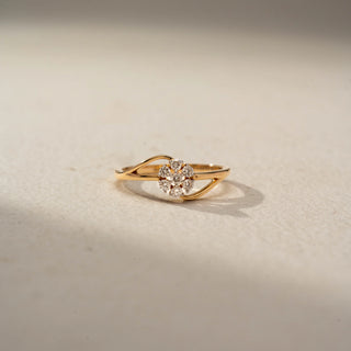 Front view of a floral diamond ring in 14 KT Yellow Gold, featuring a flower-shaped cluster of round lab-grown diamonds nestled within a flowing open-band design, displayed against a beige backdrop.