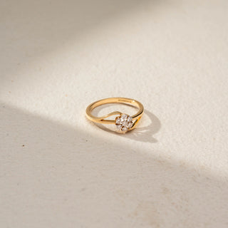 Side view of a floral diamond ring in 14 KT Yellow Gold, featuring a flower-shaped cluster of round lab-grown diamonds nestled within a flowing open-band design, displayed against a beige backdrop.