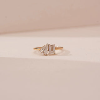 Front view of Reia’s 18 KT Yellow Gold Modern Twin Diamond Proposal Ring. Captured against a cream backdrop, the layout highlights the brilliant contrast of the side-by-side diamonds.