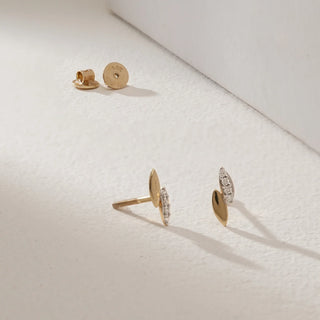 Gleaming Petite Diamond Stud Earrings in 14KT Yellow Gold, designed in a delicate leaf-like silhouette with one half polished gold and the other half set with round-cut diamonds, displayed with Bombay screw backs on a soft light background.