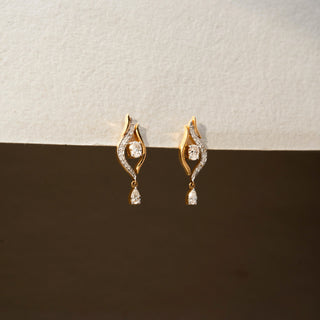 Angle view of diamond drop earrings in 14 KT Yellow Gold, featuring flowing pavé-set curves, floating round diamonds, and pear-shaped dangling accents against a neutral backdrop.