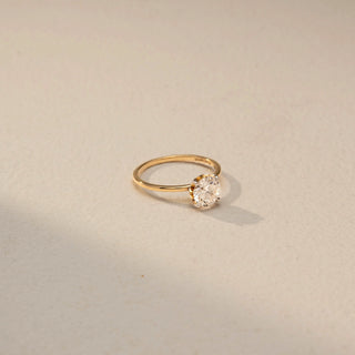 Side view of a yellow gold solitaire ring featuring a round brilliant-cut diamond in a four-prong setting, highlighting the elevated profile and delicate, minimalist band.