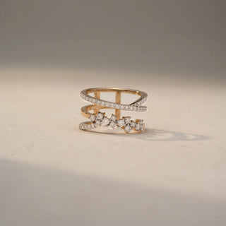 Front view of a diamond wrap ring in 14 KT Yellow Gold, featuring pavé-set diamond bands and floral-inspired diamond clusters in an elegant open crossover design, displayed against a beige backdrop.