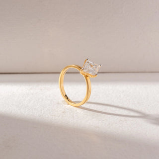 Angled view of kite-shaped step-cut diamond ring in yellow gold with a slim band, set on a soft neutral background, highlighting elevated setting and clean, geometric brilliance.
