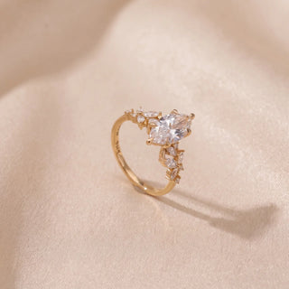 Angled view of a 14KT Yellow Gold ring with a marquise-cut diamond and marquise-cut side diamonds.