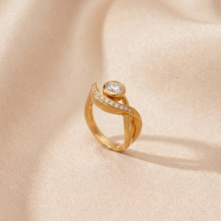 Angled view of a 14KT Yellow Gold ring with a round-cut diamond and pavé diamond curved band.