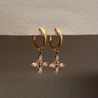 Side view of floral diamond drop hoop earrings in 14KT Yellow Gold, featuring marquise-cut lab-grown diamonds in a cross flower motif. Captured against a beige backdrop, highlighting elegant brilliance.