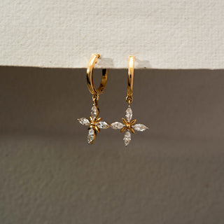 Angled side view of floral diamond drop hoop earrings in 14KT Yellow Gold, featuring marquise-cut lab-grown diamonds in a cross flower motif. Captured against a beige backdrop, highlighting delicate sparkle.