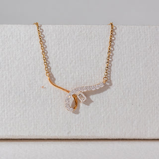 Front view of diamond pendant necklace in yellow gold, featuring a curved lab-grown diamond-studded design with a central baguette diamond. Displayed against a soft beige textured background.