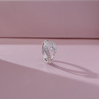 Side angled view of solitaire diamond ring in white gold, featuring a round lab-grown diamond set within a curved teardrop frame lined with round diamonds. Set on a soft pink backdrop, it highlights elegant sparkle.