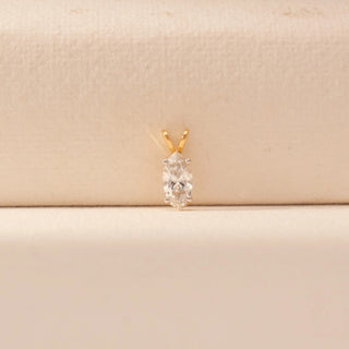 Front view of a 14KT yellow gold pendant featuring a marquise-cut diamond, set against a beige background.