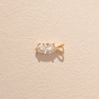 Top view of a 14KT yellow gold pendant featuring a marquise-cut diamond, set against a beige background.