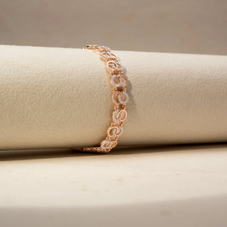 Side  view of a diamond bracelet in 14 KT Rose Gold, featuring interlocking oval motifs accented with pavé-set diamonds in a graceful linked design, displayed against a soft beige backdrop.

