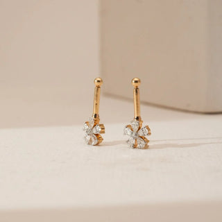 Side view of floral diamond Koppu in 18KT Yellow Gold, featuring pear-shaped diamonds arranged in a blooming cluster with a sleek gold stem, set against a soft beige backdrop.