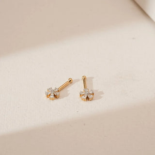 Top angled view of floral diamond Koppu in 18KT Yellow Gold, featuring pear-shaped diamonds forming a blooming cluster with a polished gold stem, set against a soft beige backdrop.