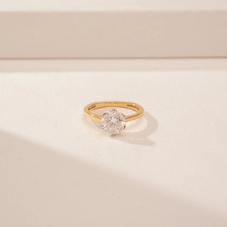 Close-up view of a 14KT Yellow Gold diamond ring with a round floral-style centre and a sleek plain band.
