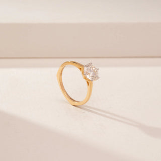 Angled view of a 14KT Yellow Gold diamond ring with a round floral-style centre and a sleek plain band.