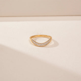 Close up view of a 14KT Yellow Gold diamond ring, featuring a curved band with a row of round diamonds.