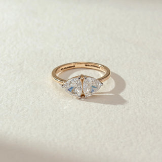 Top view of marquise diamond ring in yellow gold, featuring a centred marquise-cut lab-grown diamond secured with dual prongs. Placed on a textured beige surface, the design casts a soft shadow.
