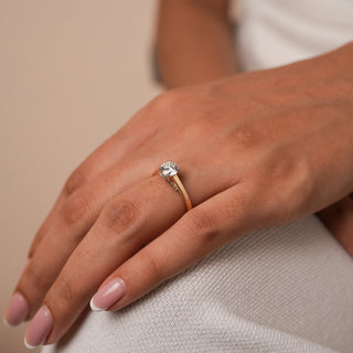 Reia's Golden Vow Solitaire Diamond Ring, worn on a model's hand, featuring a round-cut lab-grown diamond set in 14KT yellow gold, shot against a neutral cream background.