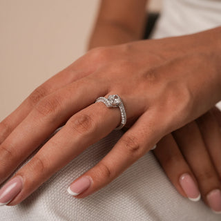 Reia's Twinned Souls Diamond Vow Ring is worn on the hand, crafted in 14KT white gold with an oval-cut EF-VVS diamond and intertwined pave bands.