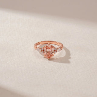 Close-up view of a 14KT Rose Gold ring featuring a pink oval-cut centre diamond with marquise and round diamond side accents.