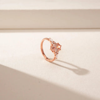 Angled view of a 14KT Rose Gold ring featuring a pink oval-cut centre diamond with marquise and round diamond side accents.