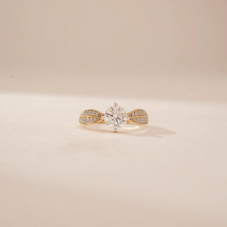 Front view of a 14KT Yellow Gold diamond ring, featuring a round centre diamond and leaf-shaped diamond-set shoulders.