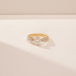 Close-up view of a 14KT Yellow Gold diamond ring, featuring a round centre diamond and leaf-shaped diamond-set shoulders.