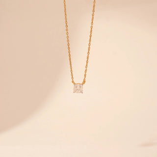 Front view of a 14KT yellow gold necklace, featuring a square cushion-cut diamond pendant. Set against a beige backdrop.