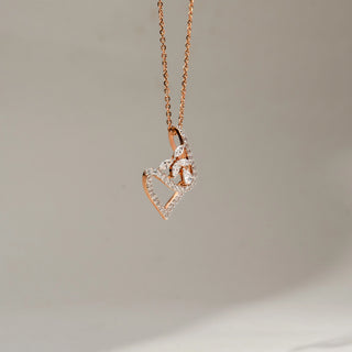 Side view close-up of a rose gold pendant necklace with a diamond-studded open teardrop design and floral diamond motif, suspended from a delicate chain against a soft neutral background.