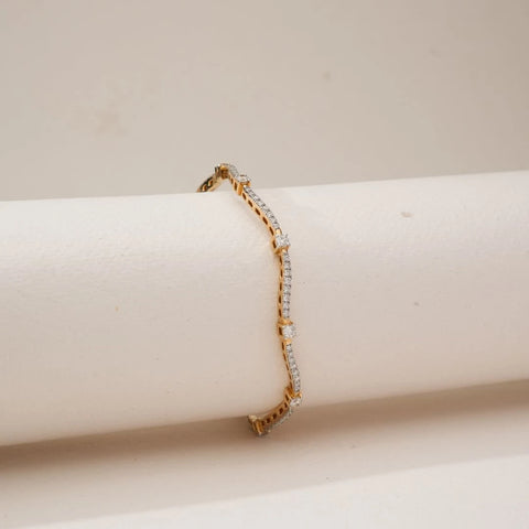 Side view of Golden Wave Radiant Diamond Bangle in yellow gold, featuring round lab-grown diamonds set along flowing wave-shaped lines, draped over a soft neutral display form.