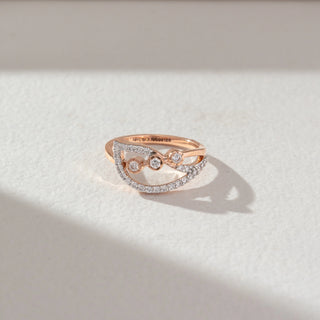 Top angled view of open diamond ring in rose gold, featuring lab-grown diamonds set along curved bands with three centred stones. Captured against a soft beige textured background.