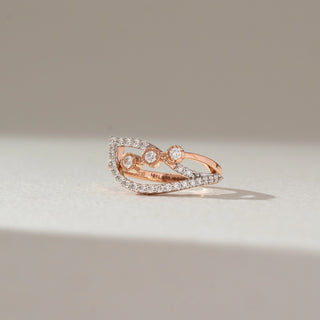 Front view of open diamond ring in rose gold, featuring lab-grown diamonds along curved bands with three centred stones. Set against a soft beige background with gentle shadows.