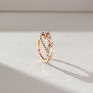 Side profile of open diamond ring in rose gold, featuring lab-grown diamonds along curved bands with three centred stones. Captured against a soft beige textured background.