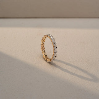 Angled view of a diamond eternity band in 14 KT Yellow Gold, featuring alternating marquise-cut and round lab-grown diamonds in a continuous floral-inspired design, displayed against a beige backdrop.