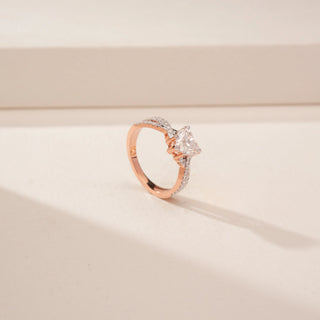 Angled view of a 14KT Rose Gold diamond ring, featuring a cushion-cut centre diamond and diamond-set twisted shoulders.