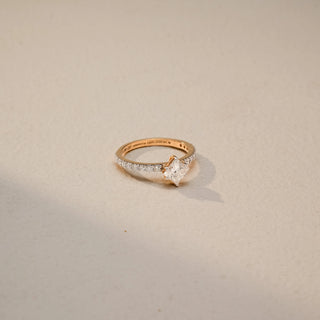 Side view of a princess-cut solitaire engagement ring in 14 KT Yellow Gold, featuring a princess-cut lab-grown diamond set on a slim pavé diamond band, displayed against a beige backdrop.