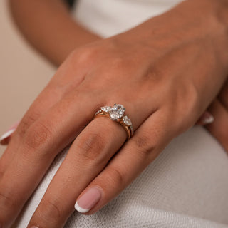 Close-up of Reia's Golden Harmony Diamond Bridal Set showing the open pear-shaped diamond band in 14KT yellow gold, captured with floral detailing in the background.