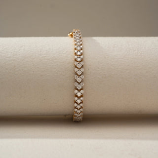 Front view of a gold bracelet featuring a repeating pattern of heart-shaped and round brilliant gemstones, elegantly displayed on a soft neutral cylindrical stand.